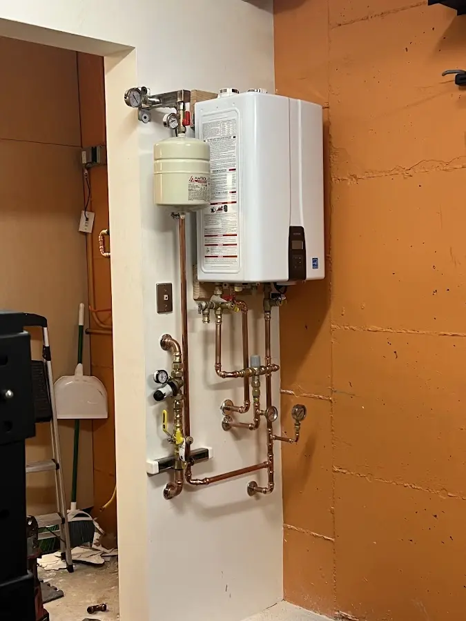Plumbing technician inspecting water heater connections in Medfield